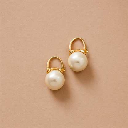Classic Pearl Drop Earrings with gold hooks on a beige background