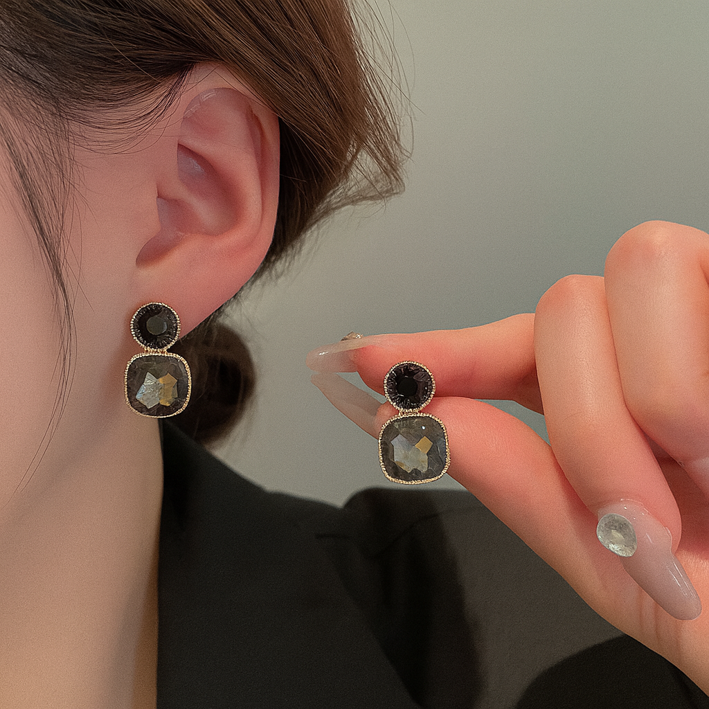 Close-up of a person wearing Noir Grace Dual Stone Stud Earring with a hand holding another earring.