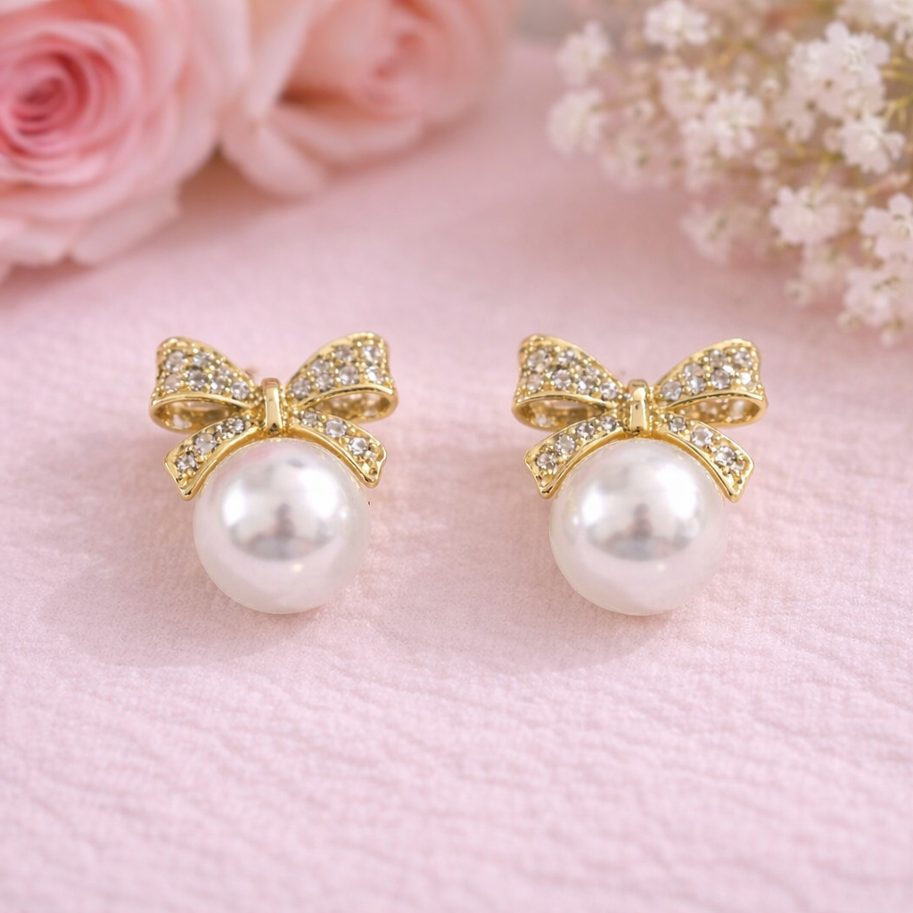 Pearl earrings with gold bows on a pink background with flowers
